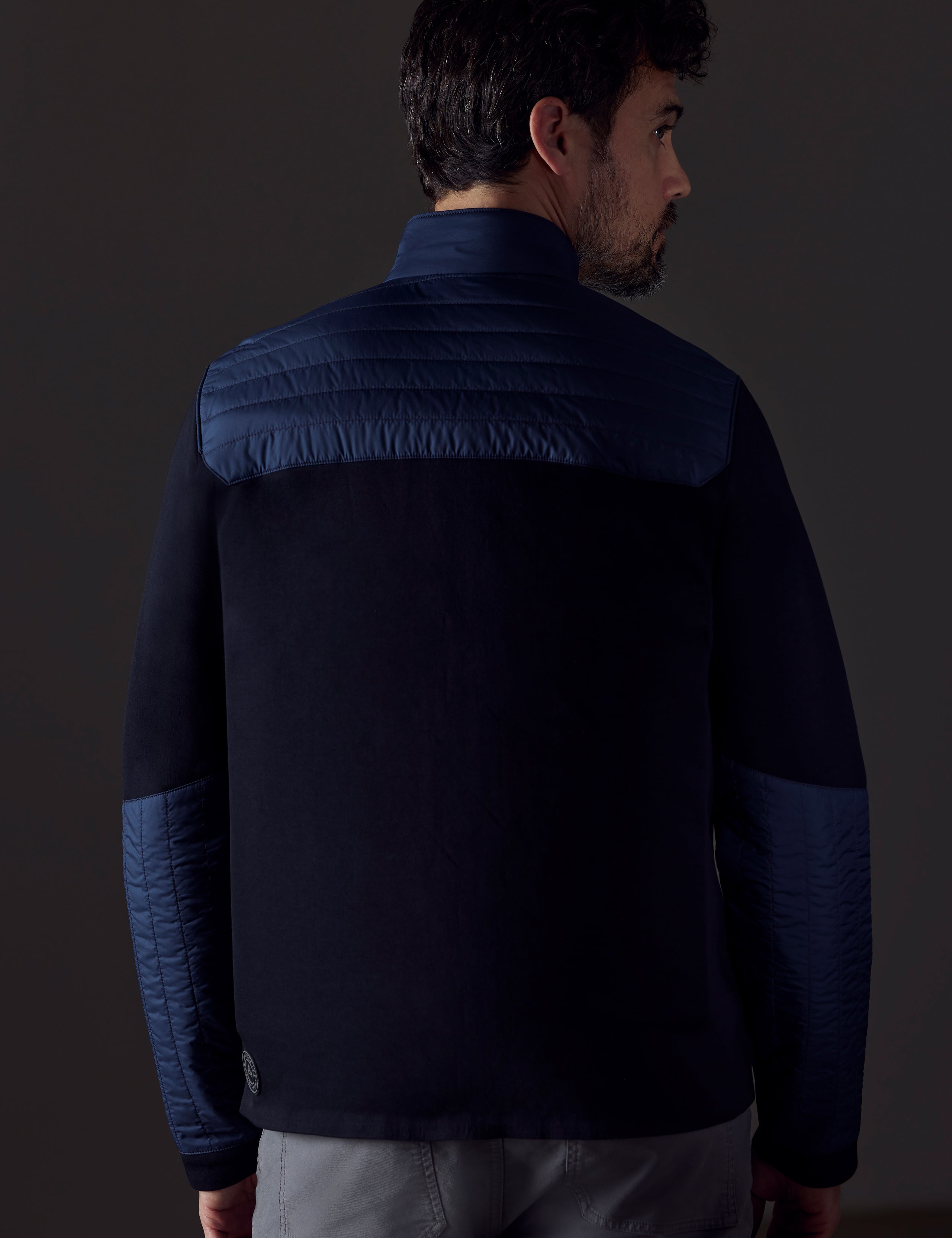 Rear body view of man wearing Watts Technical Jacket in Total Eclipse dark blue from AETHER Apparel.