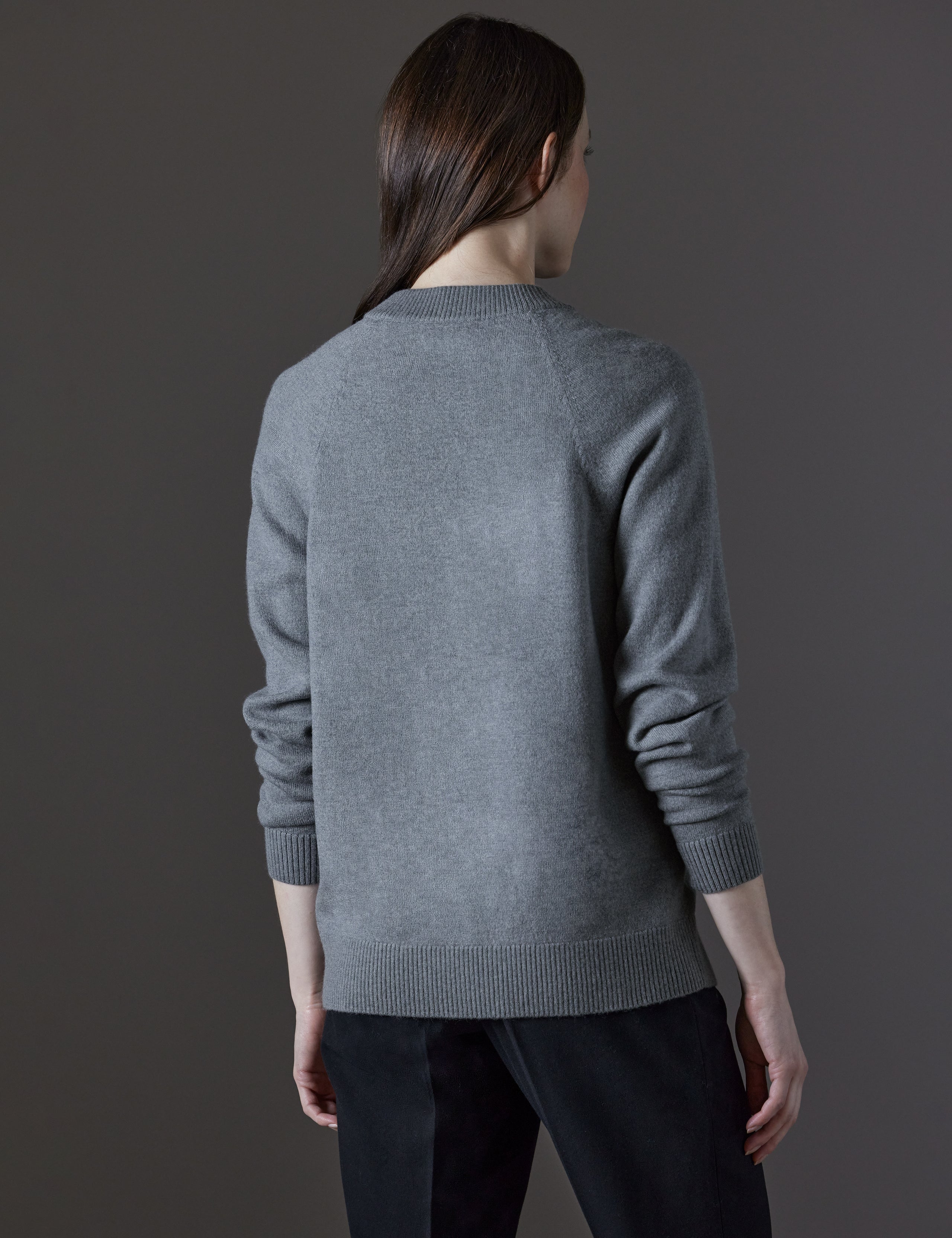 Rear angled view of woman wearing Mosie Sweater in Light Heather Grey from AETHER Apparel.