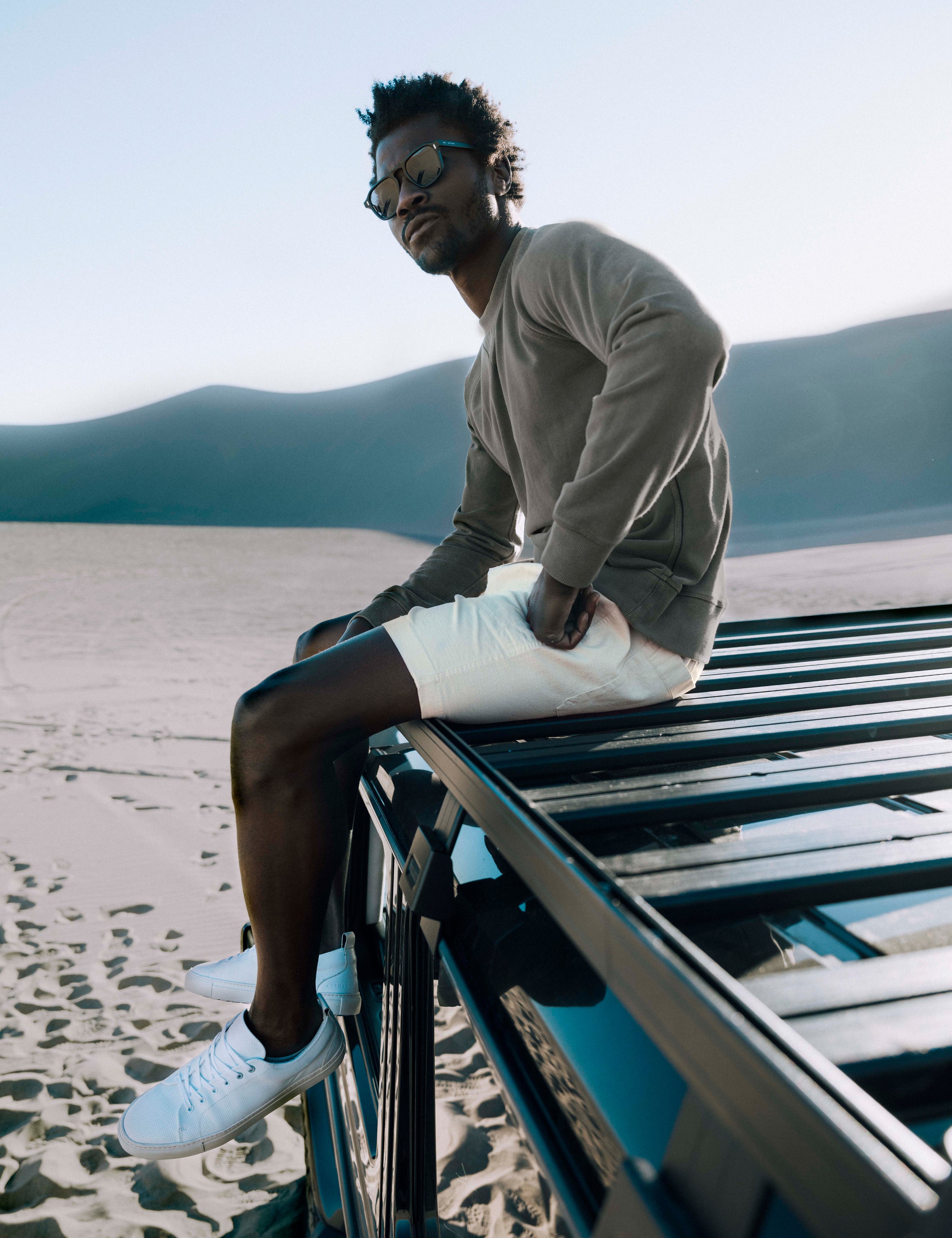 Outdoor lifestyle image of man sitting on roof of truck wearing Norton Cotton Ripstop Short in Bone white from AETHER Apparel.