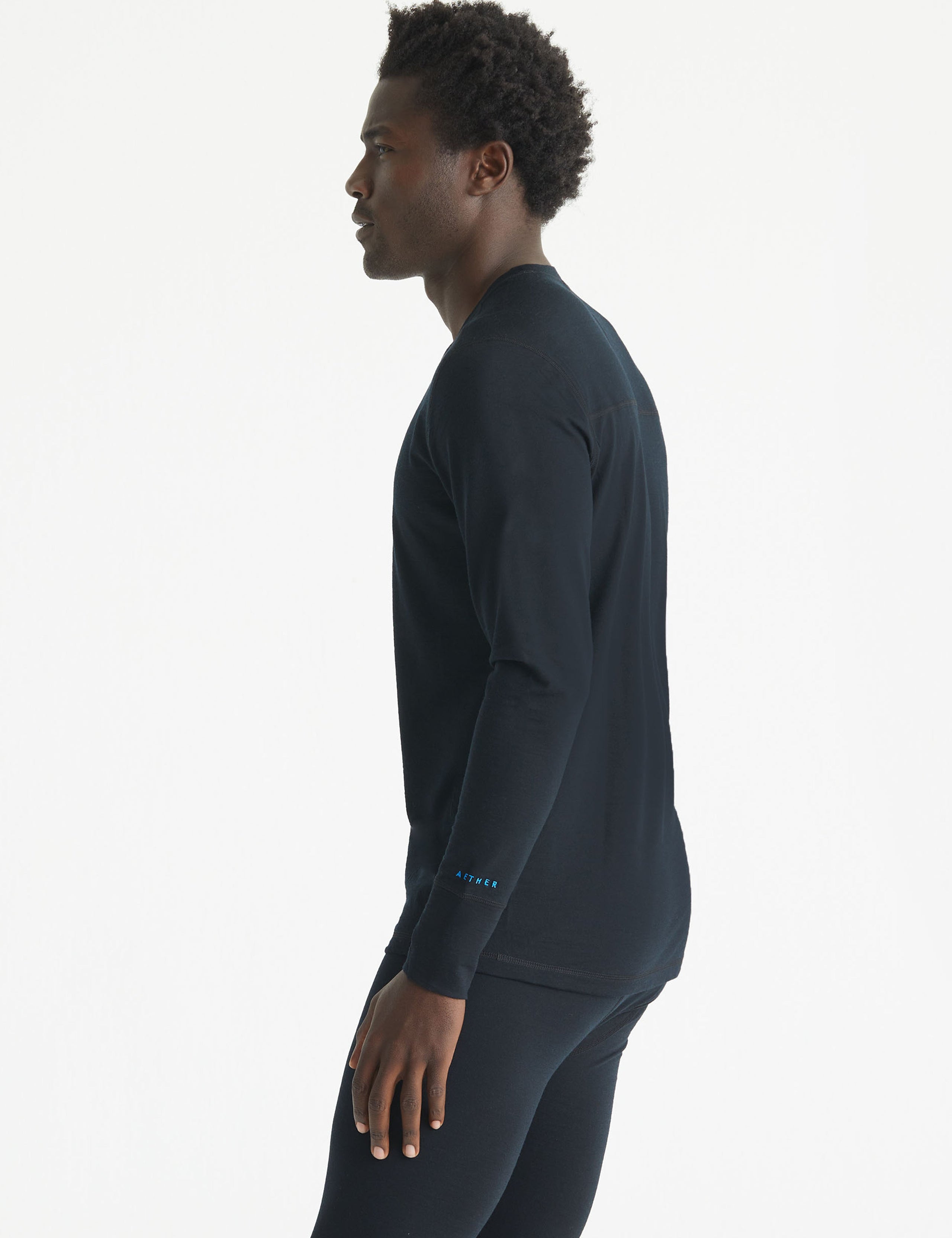 Side profile body view of man wearing Premium Merino Base Layer Crew in Jet Black from AETHER Apparel.