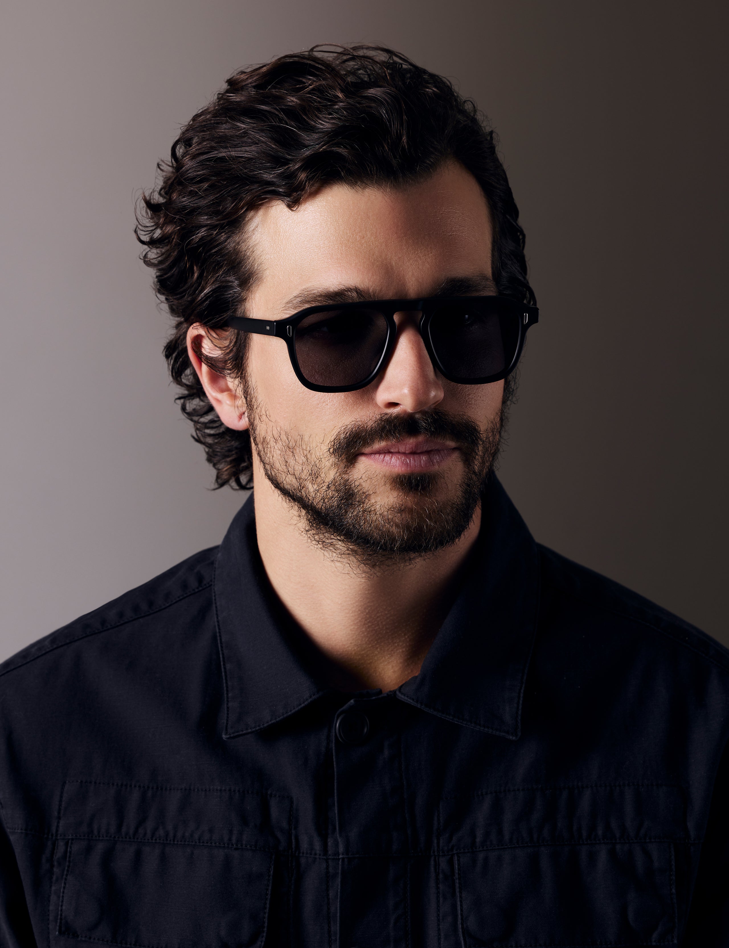 Front right 3/4 view of man wearing Sequoia Sunglass in Matte Black with Grey Lens from AETHER Apparel.