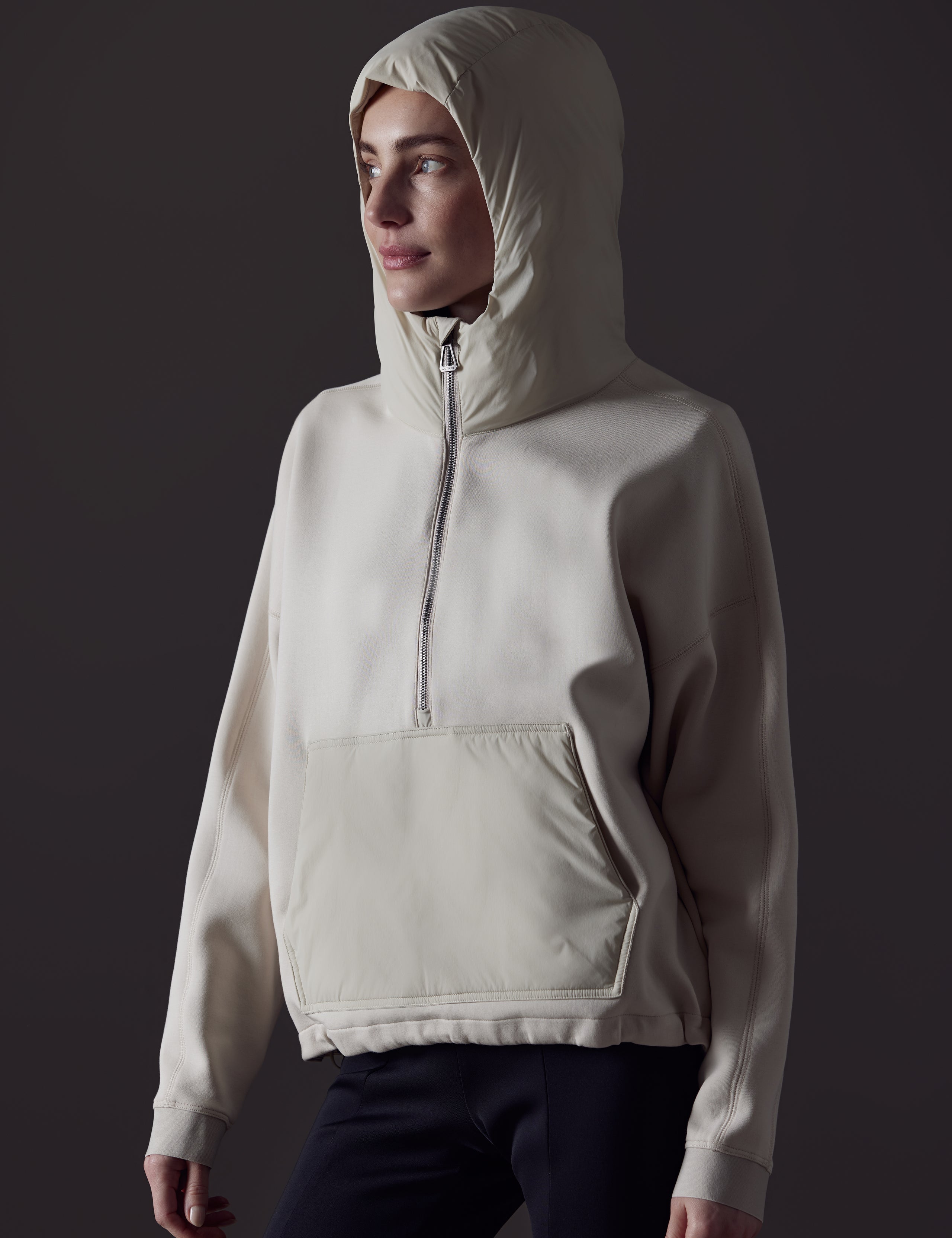 Front angled view of woman wearing Align Hooded Anorak in Bone white from AETHER Apparel with hood up. 