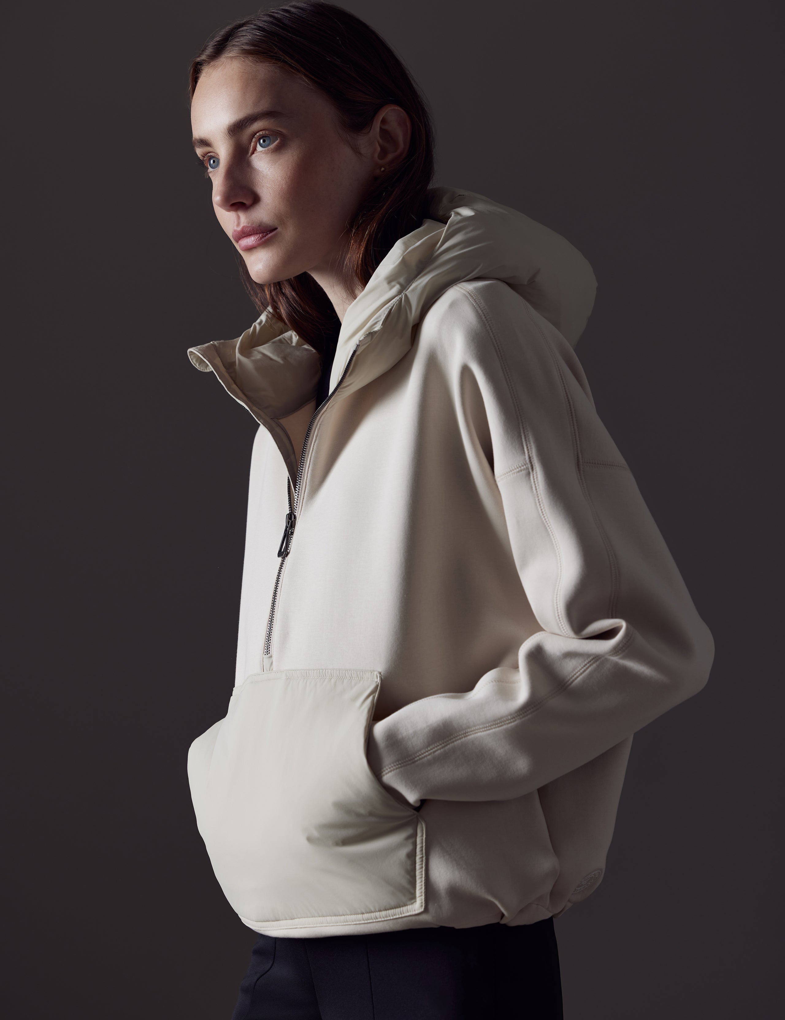 Front angled view of woman with hands in pocket wearing Align Hooded Anorak in Bone white from AETHER Apparel.