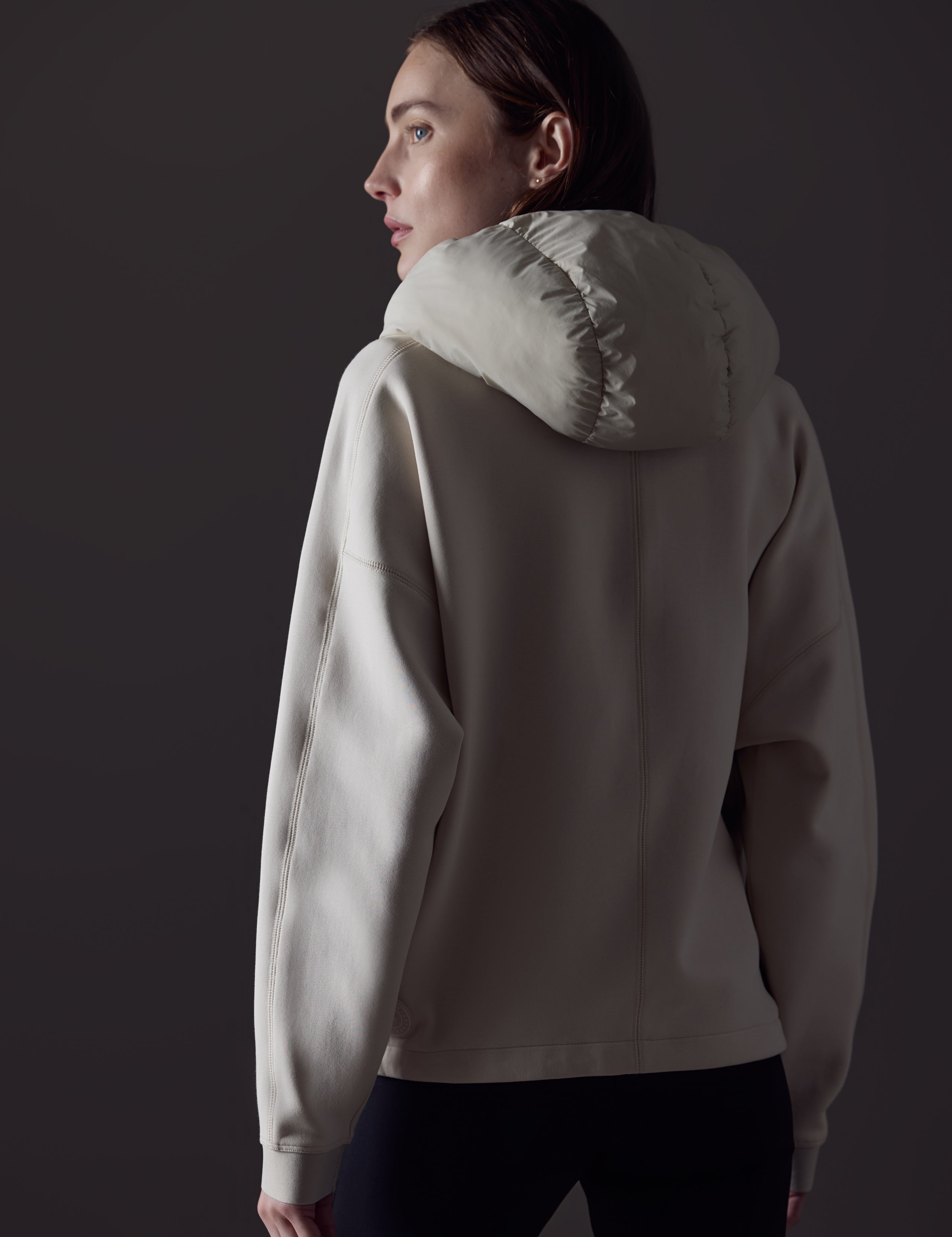 Rear angled view of woman wearing Align Hooded Anorak in Bone white from AETHER Apparel.