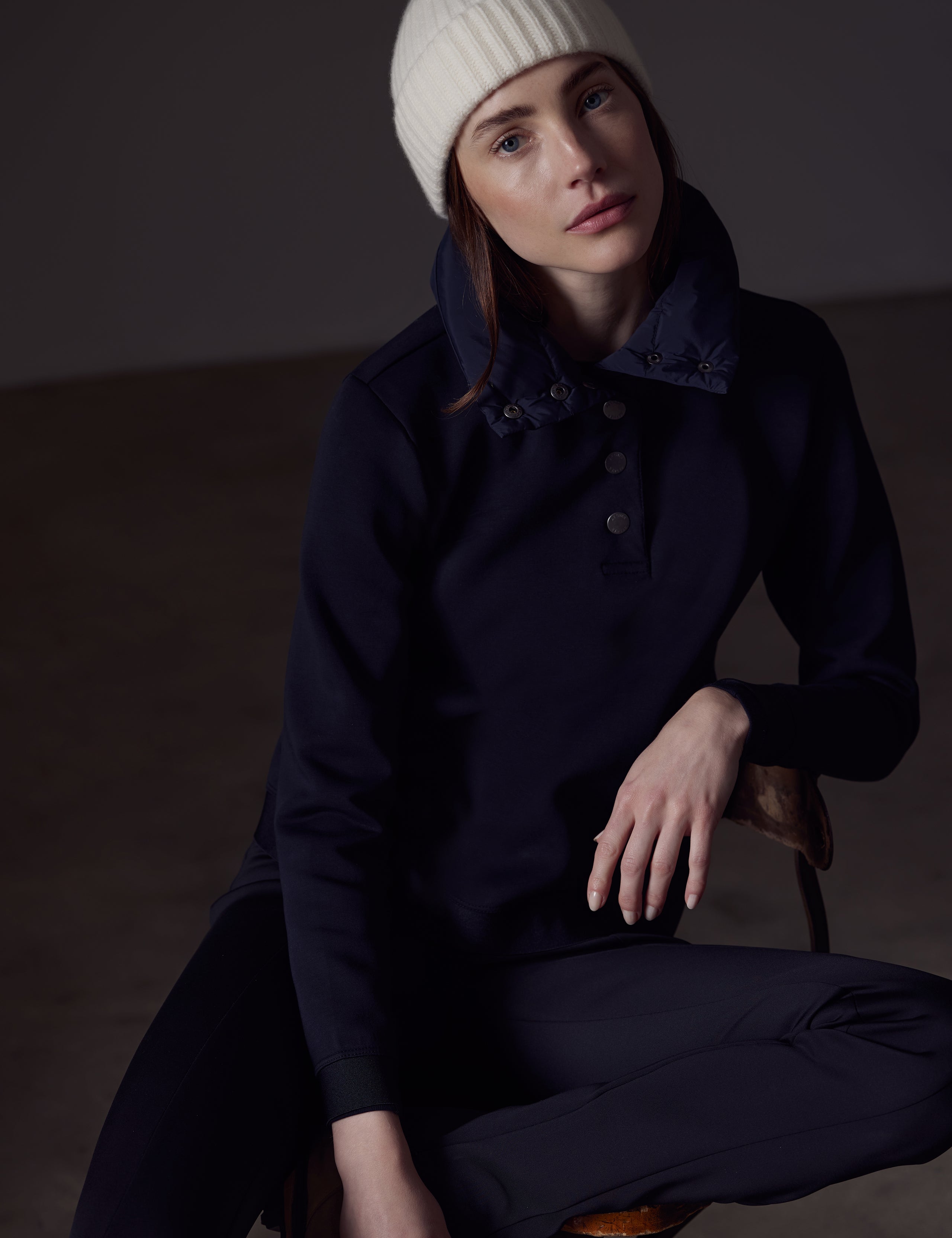 Front view of woman sitting wearing Align Pullover in Onyx Black from AETHER Apparel.