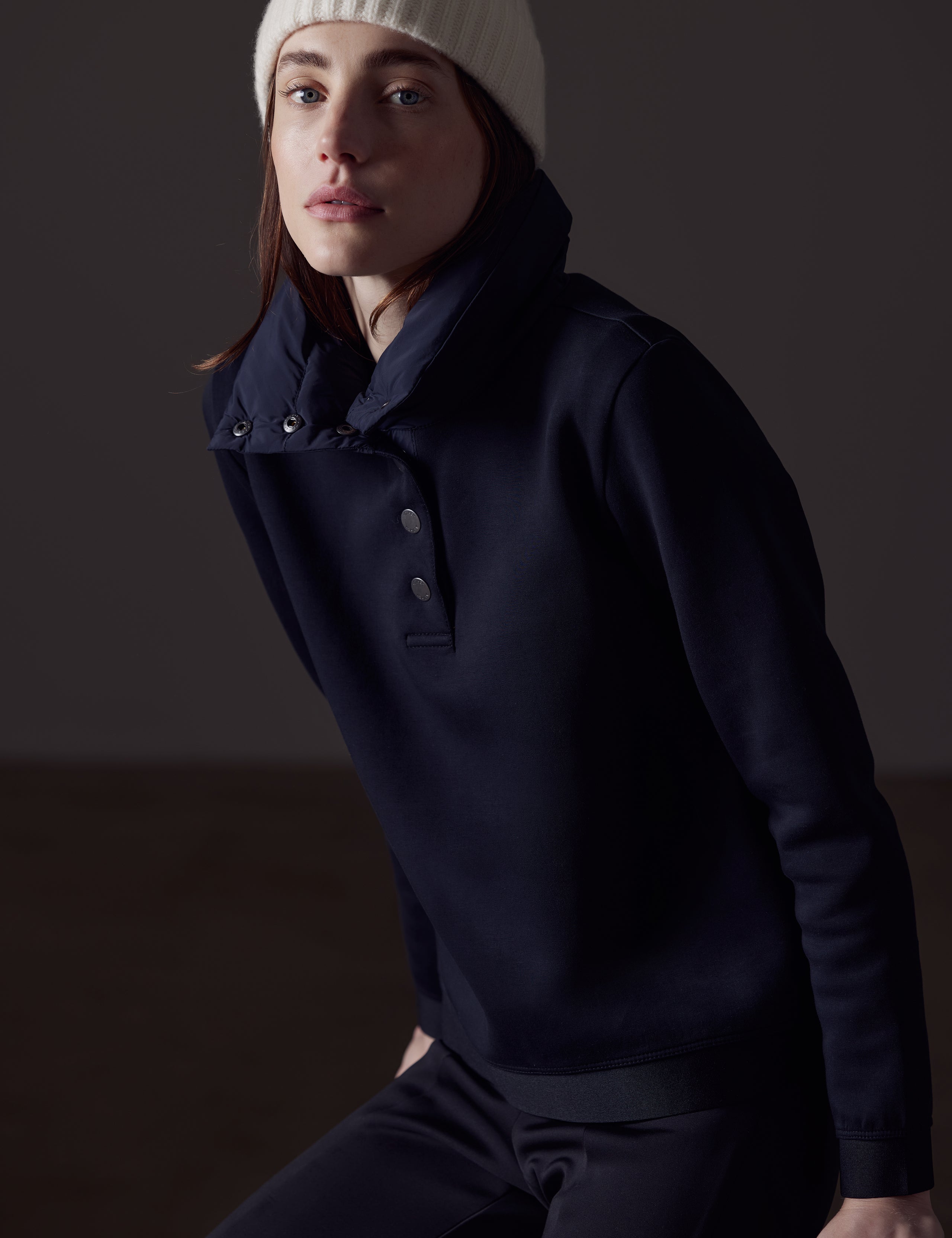 Front angled view of woman sitting wearing Align Pullover in Onyx Black from AETHER Apparel.