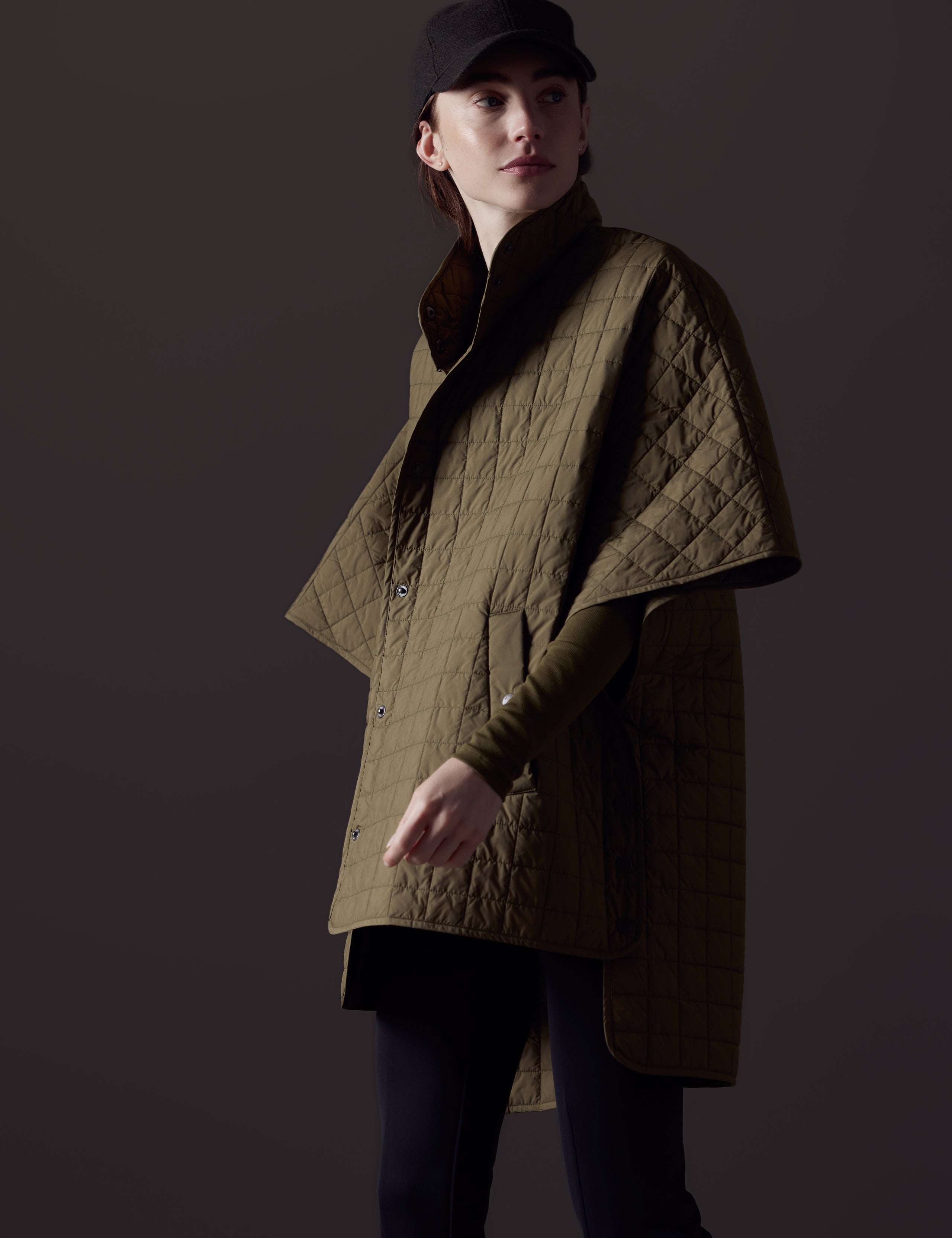 Front angled body view of woman wearing Bardo Poncho Jacket in Command Green from AETHER Apparel.