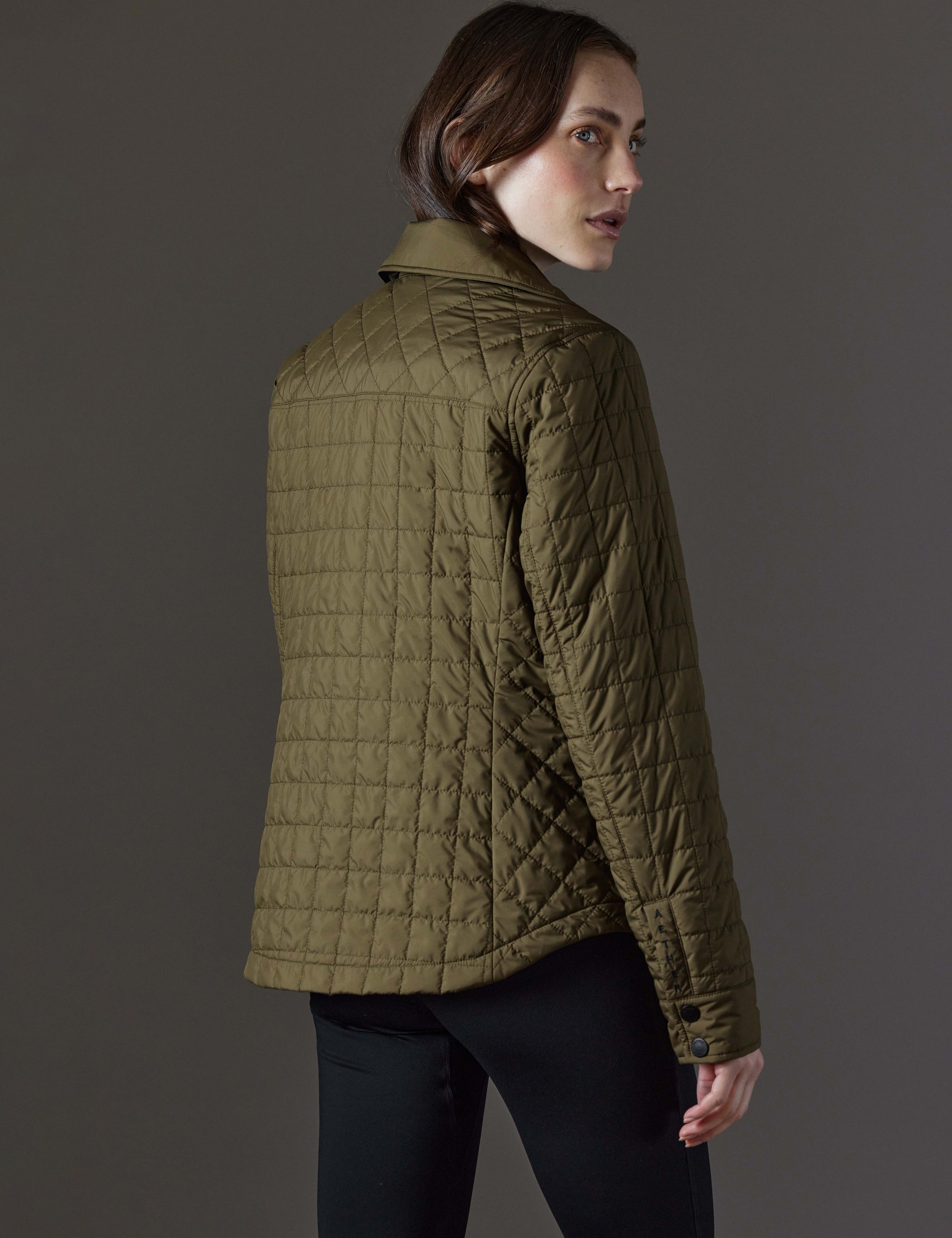 Rear angled view of woman wearing Bardo Shirt Jacket in Command Green from AETHER Apparel.