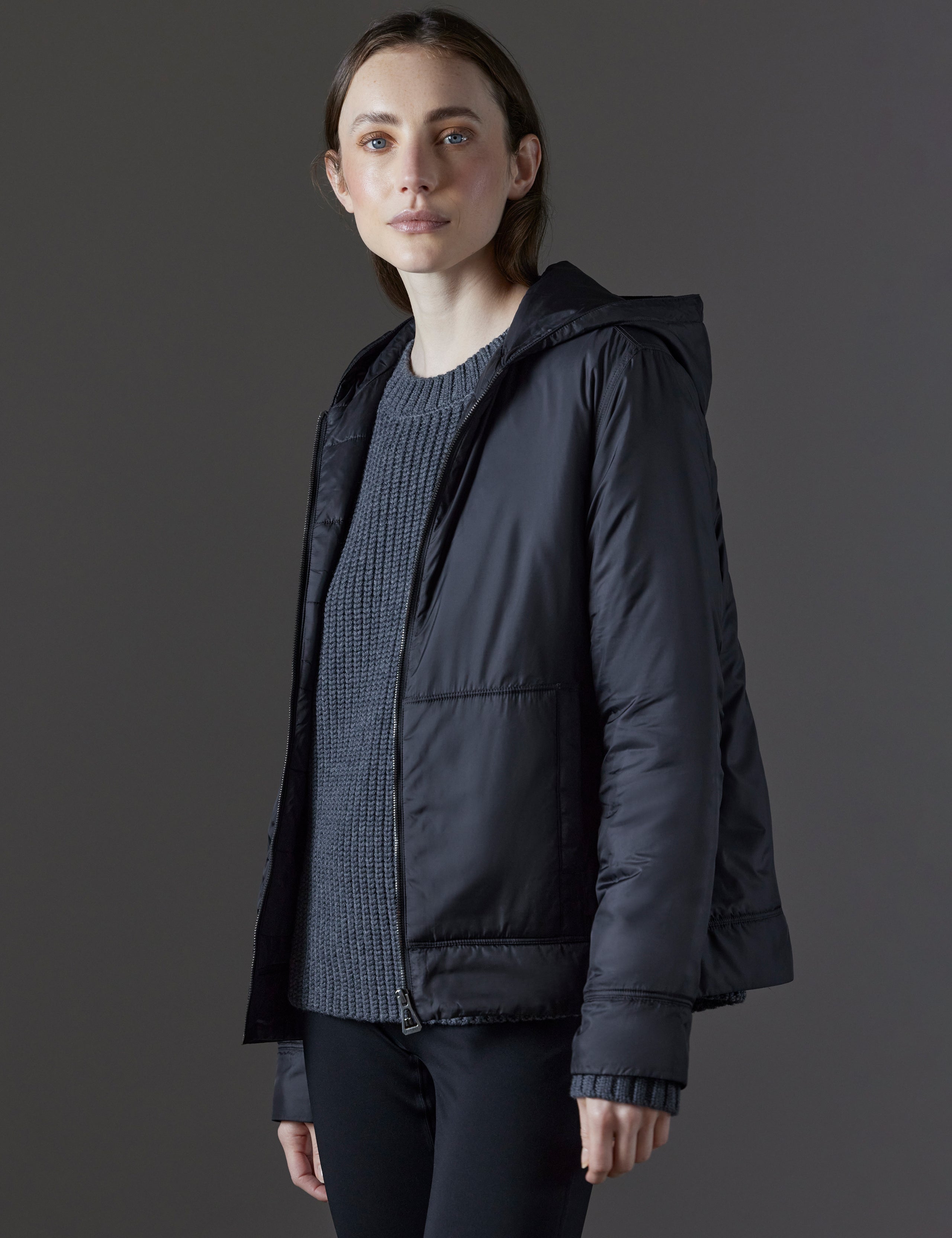 Front angled view of woman wearing unzipped Eco Space Hoodie in Onyx Black from AETHER Apparel.