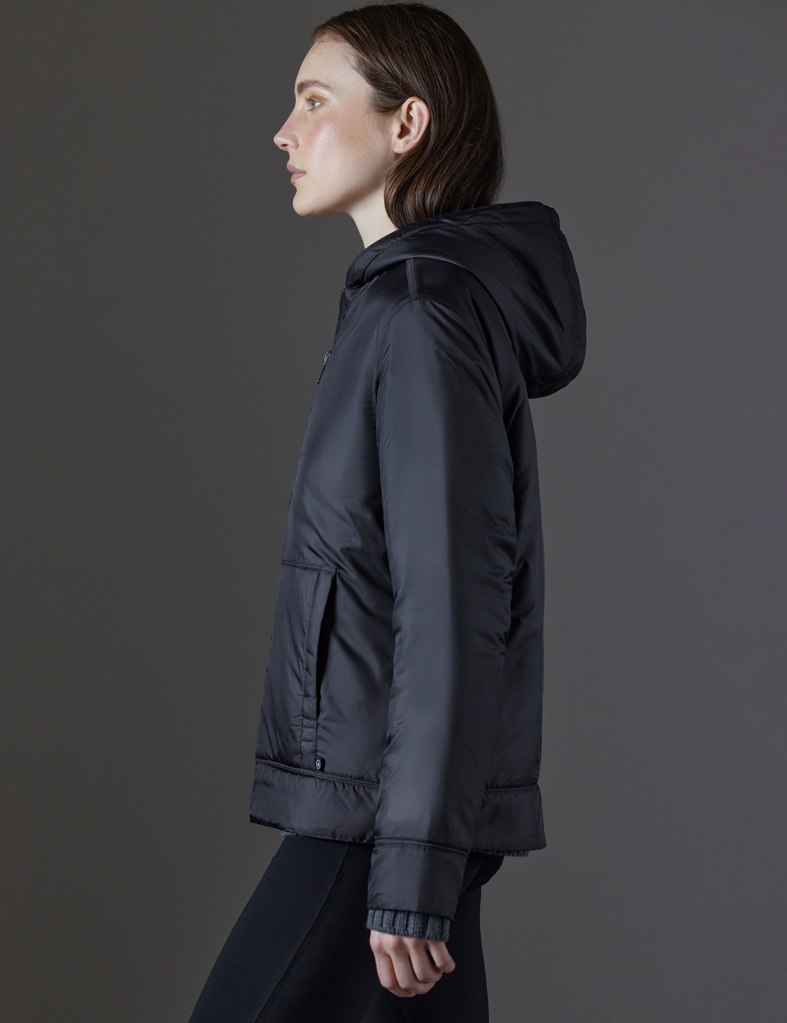 Side profile view of woman wearing Eco Space Hoodie in Onyx Black from AETHER Apparel.
