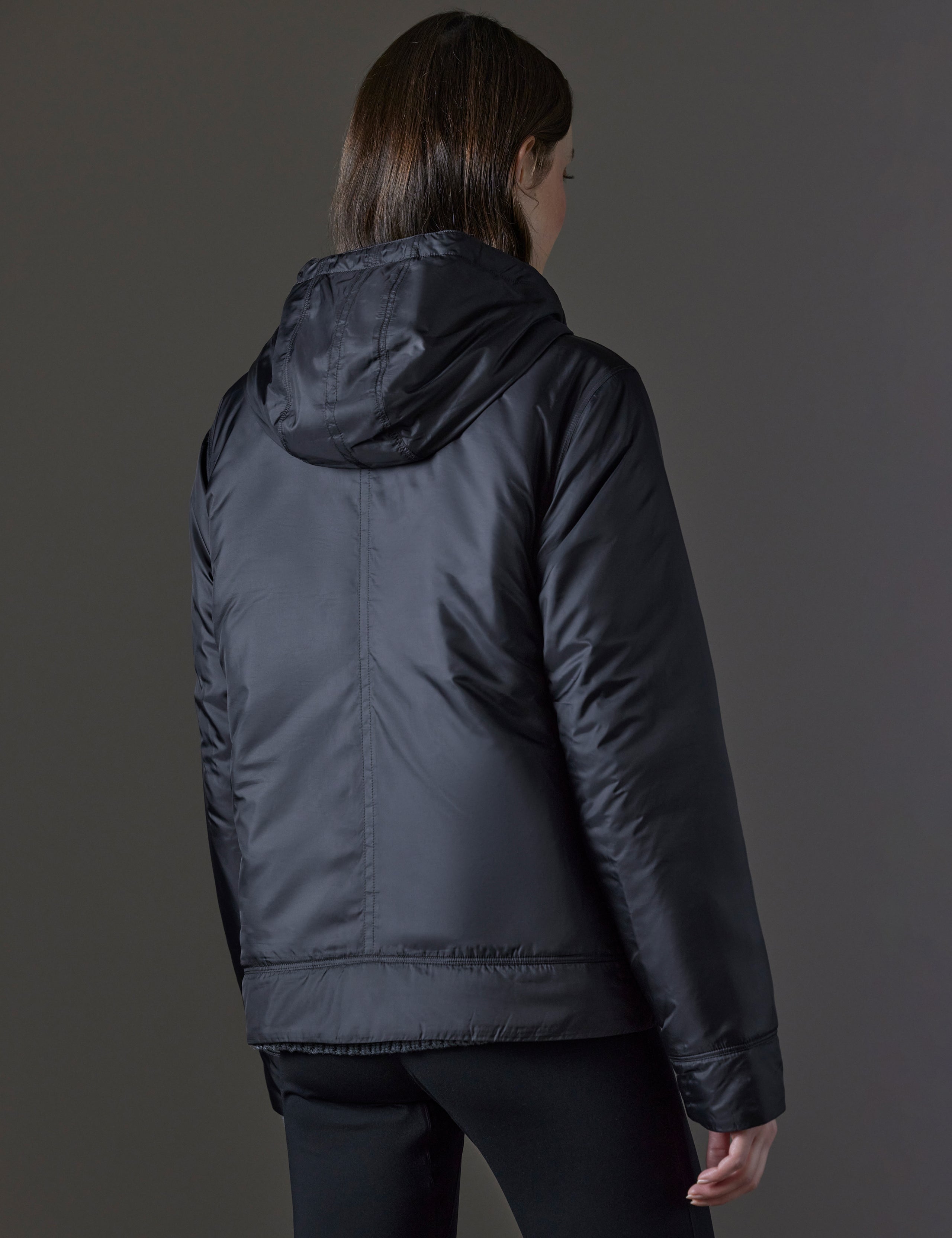 Rear angled view of woman wearing Eco Space Hoodie in Onyx Black from AETHER Apparel.
