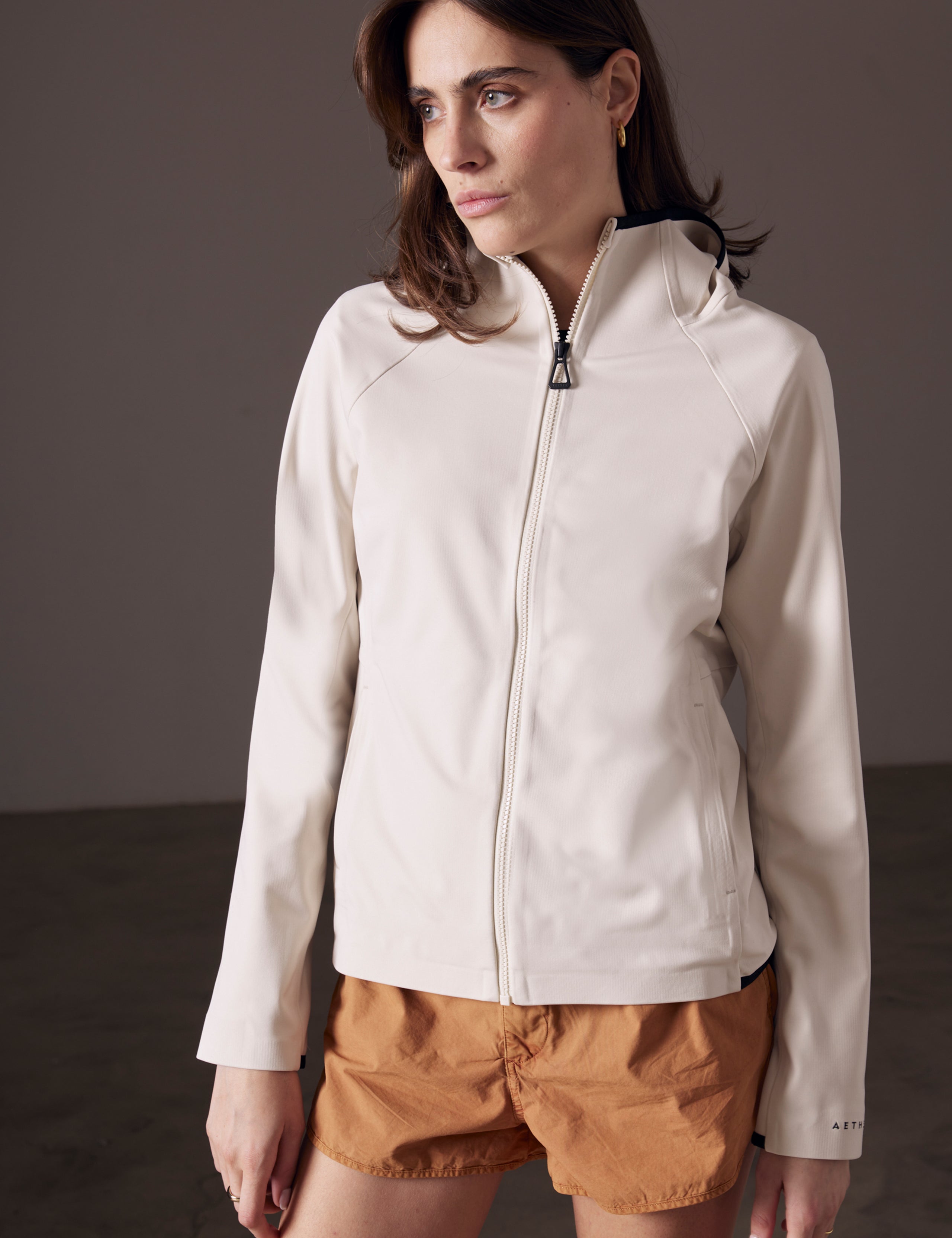 Front angled view of woman wearing Hooded Tech-Fleece Full-Zip in Bone white from AETHER Apparel.