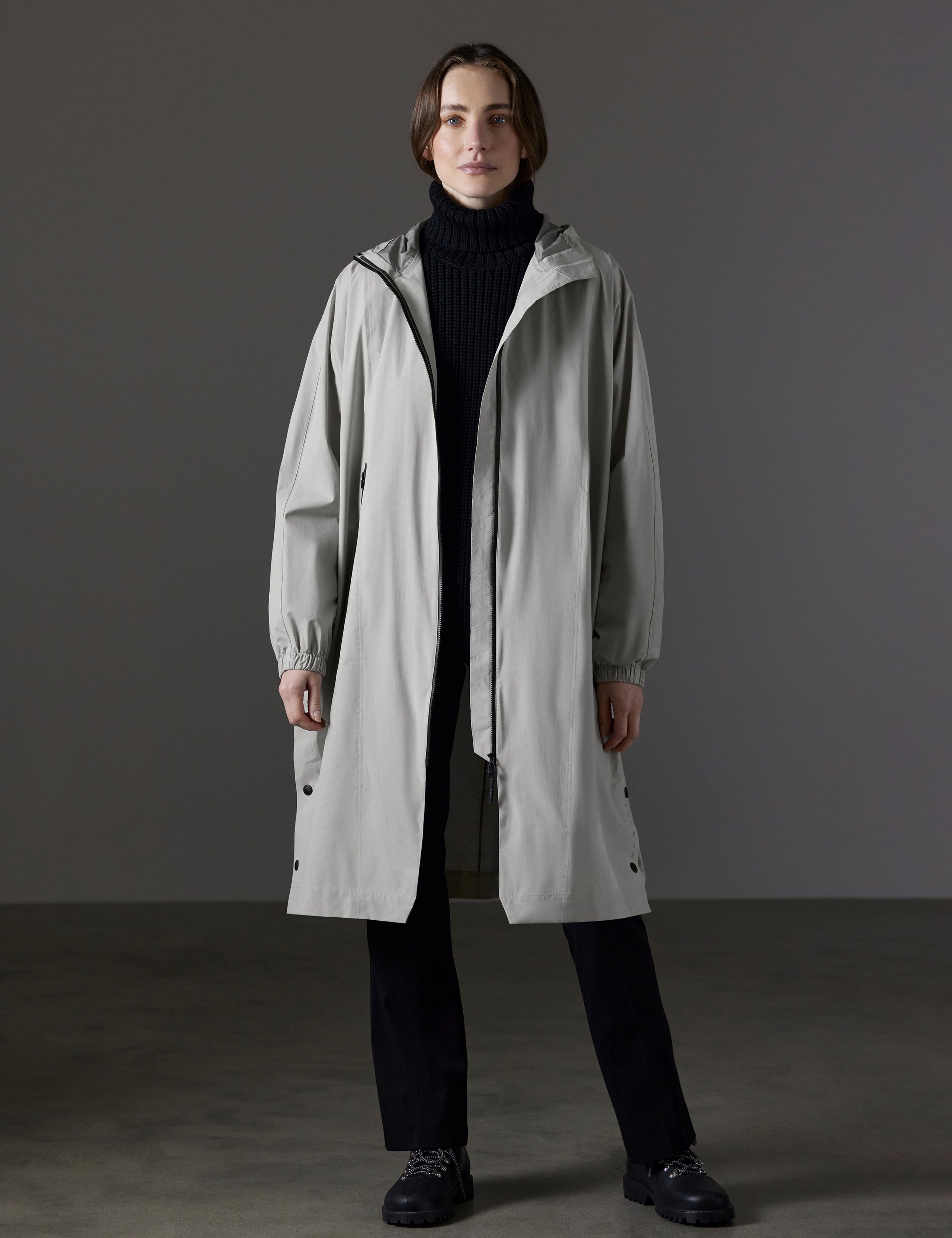 Front full-body view of woman wearing Kite Packable Rain Poncho in Stone Grey from AETHER Apparel.