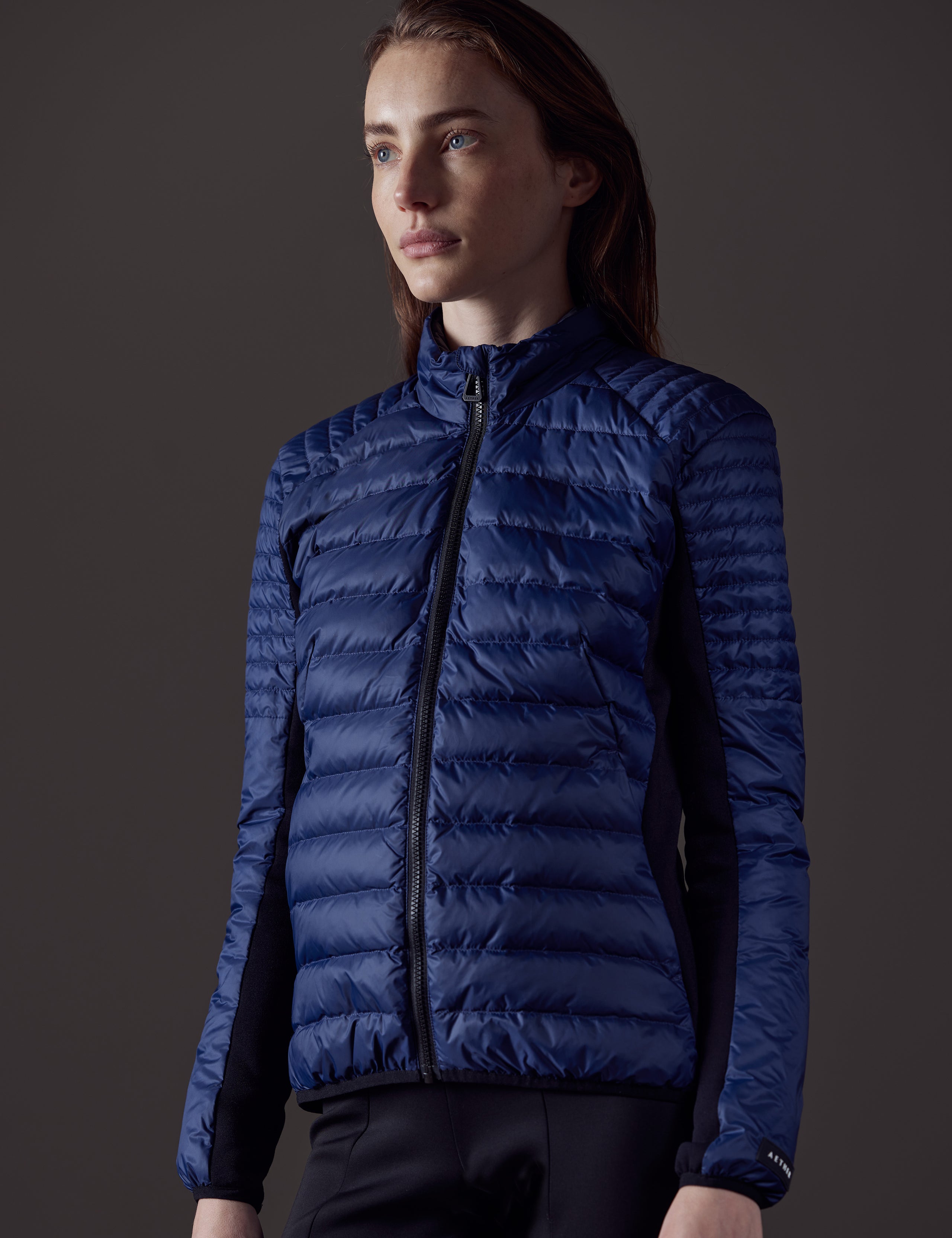 Front angled view of woman wearing Ozone Jacket in Nordic Navy blue from AETHER Apparel.