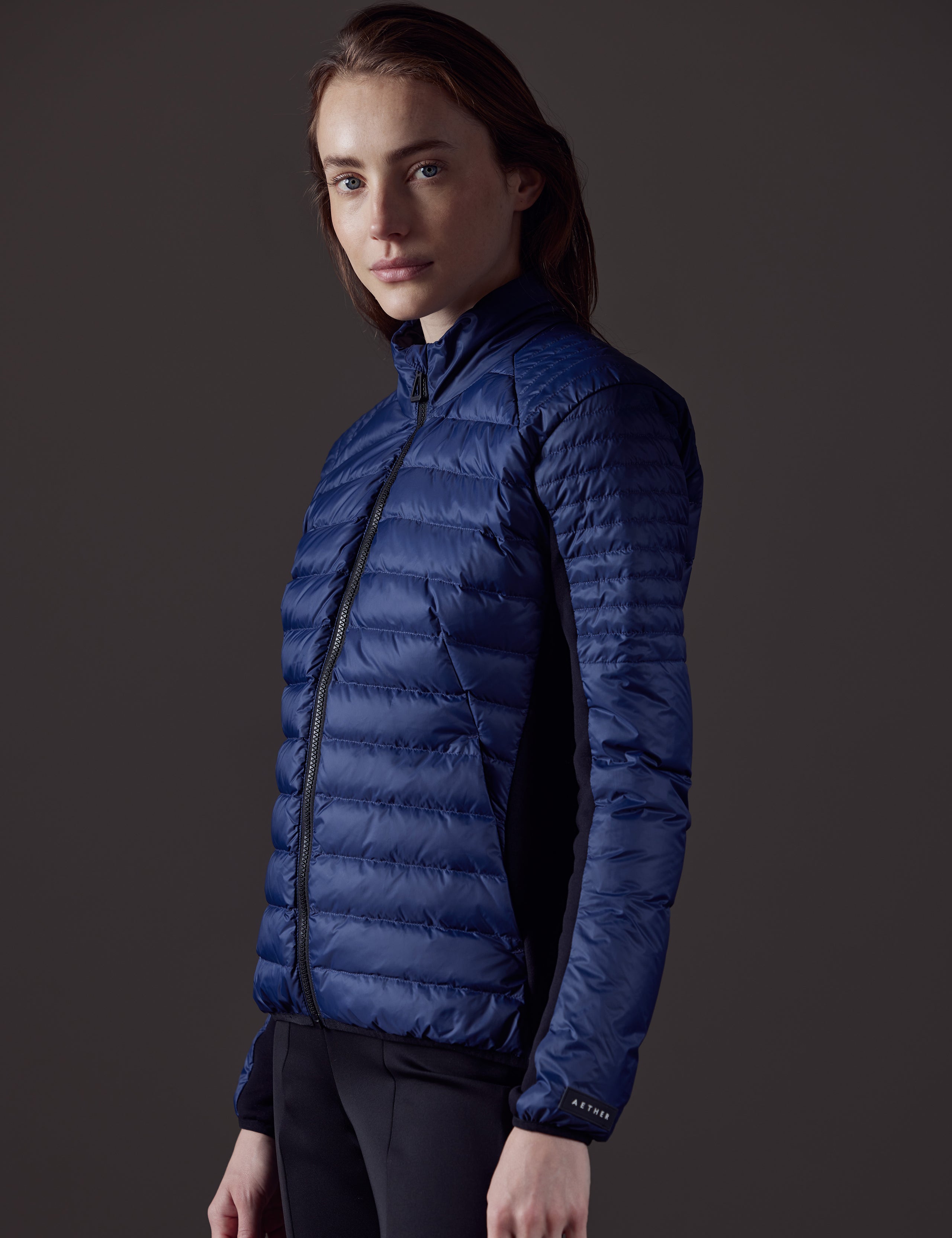 Side profile view of woman wearing Ozone Jacket in Nordic Navy blue from AETHER Apparel.