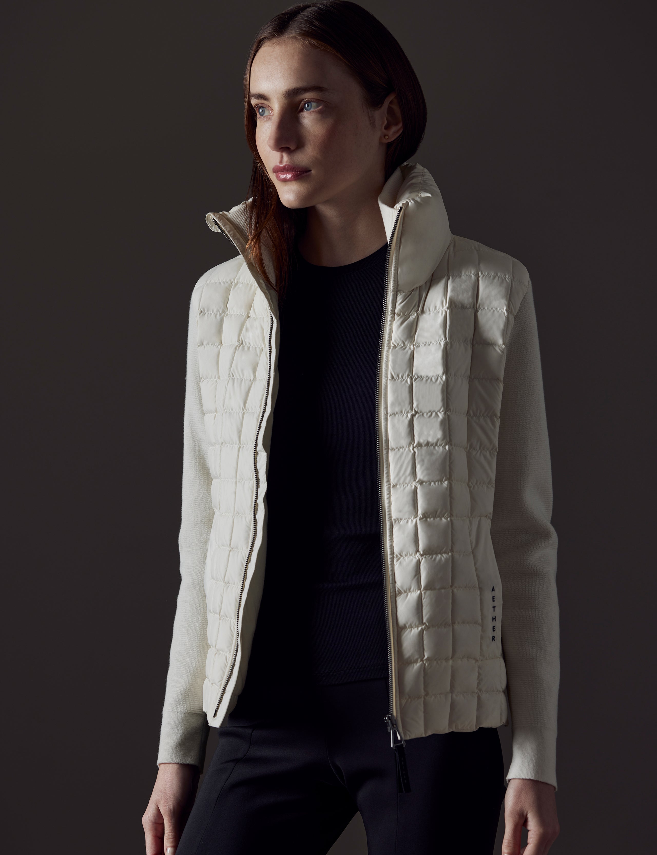 Front angled view of woman wearing unzipped Phase Full-Zip in Winter White from AETHER Apparel.