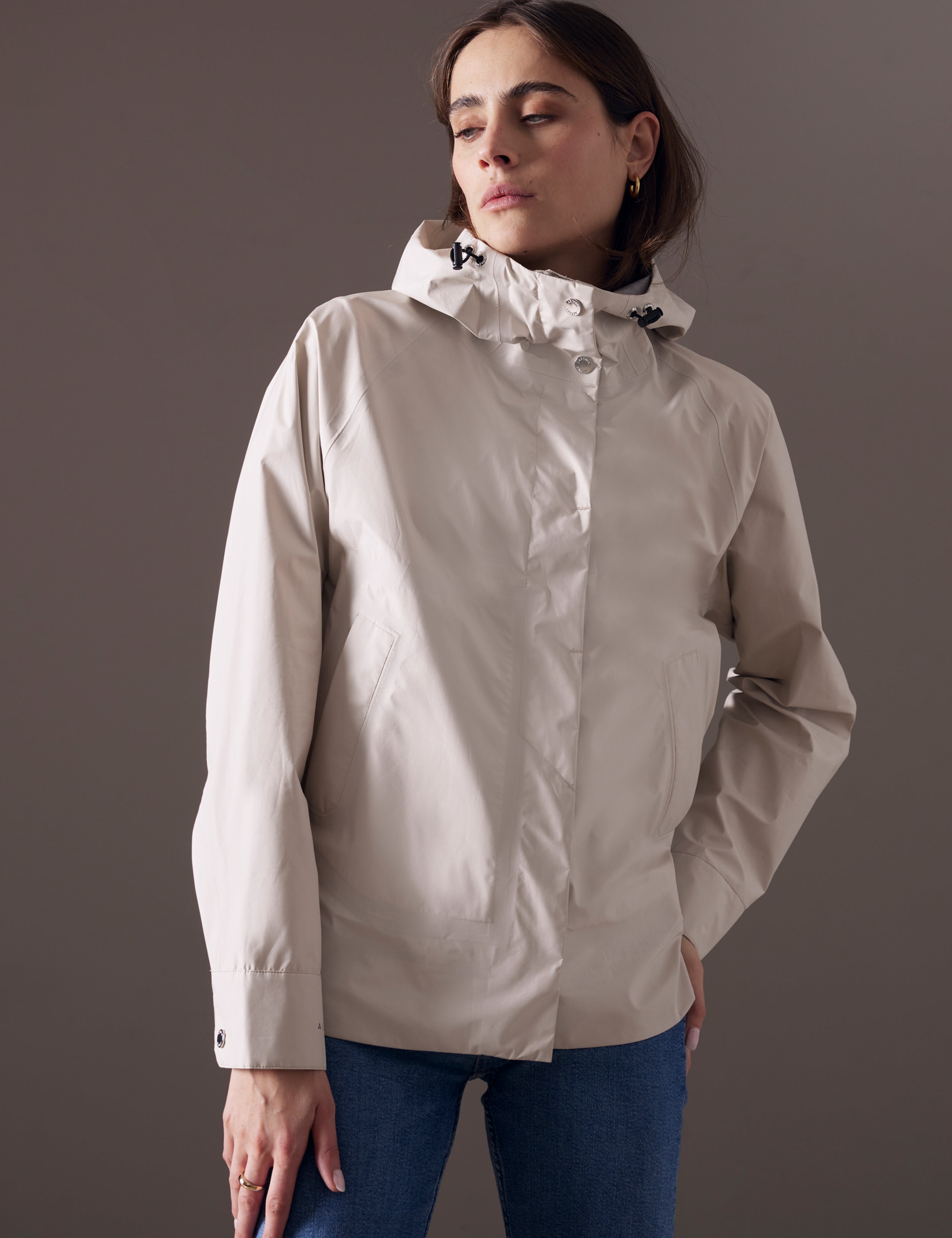 Front 3/4 body view of woman wearing Storm All-Weather Jacket in Bone white from AETHER Apparel.