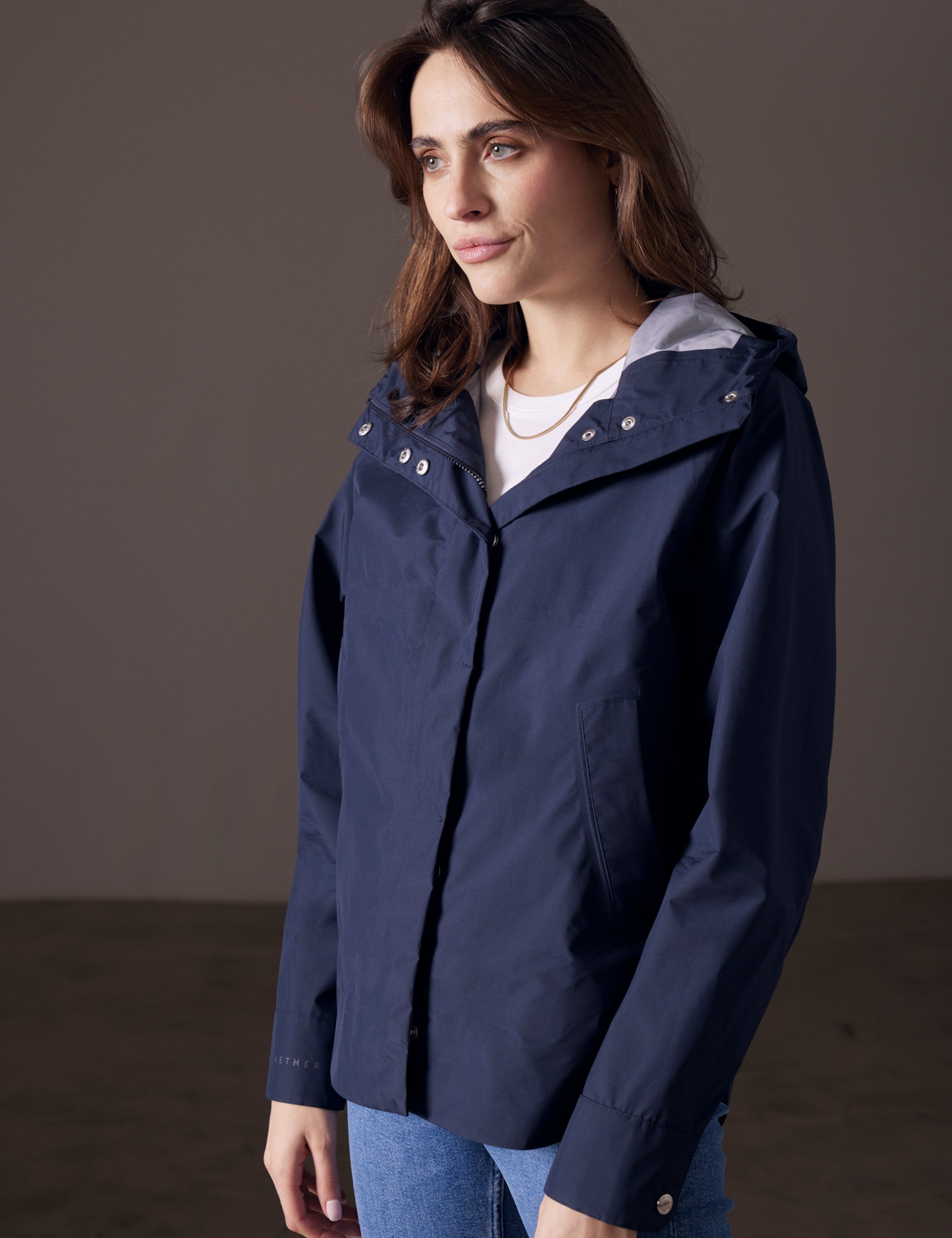 Front angled view of woman wearing Storm All-Weather Jacket in Total Eclipse dark blue from AETHER Apparel.