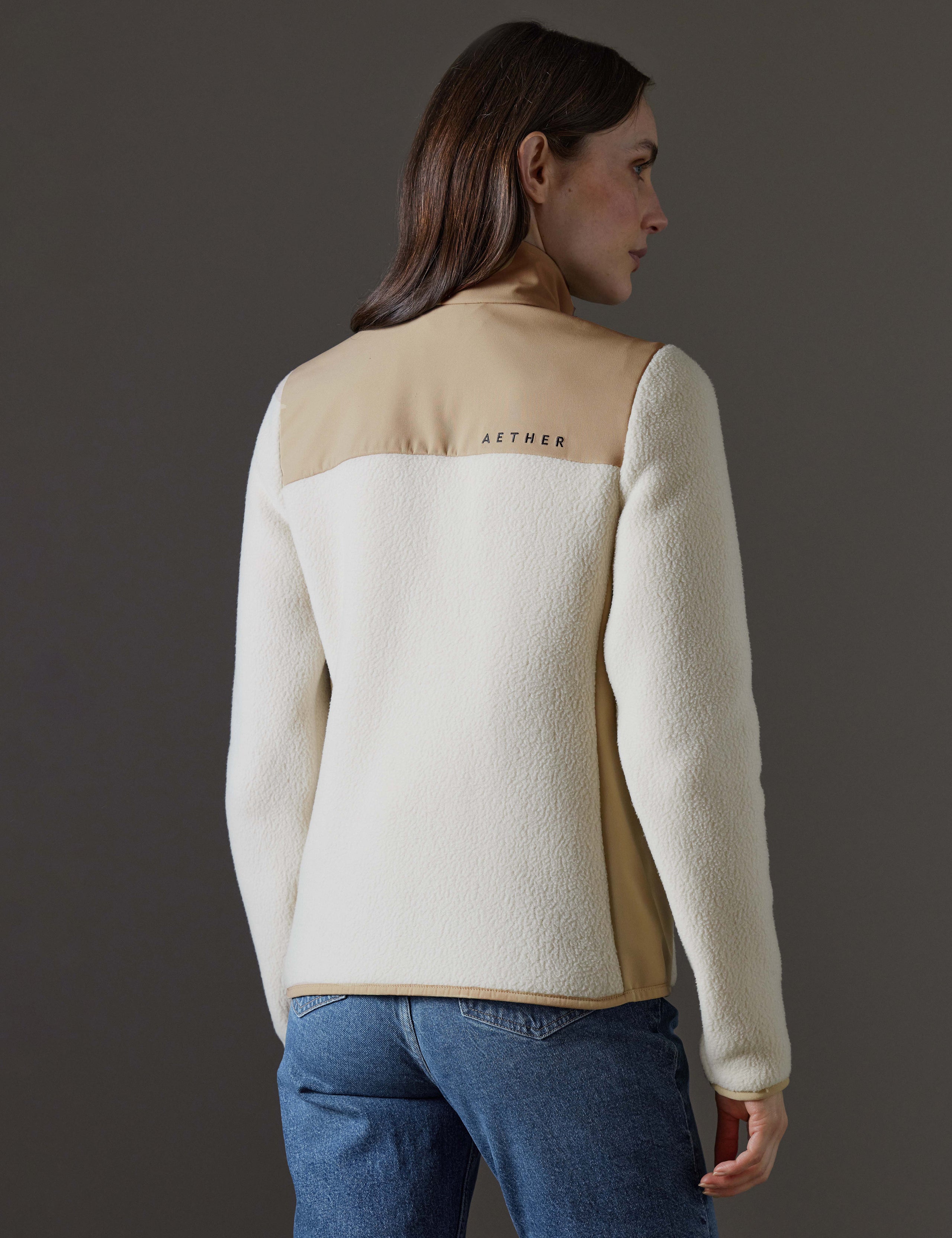 Rear angled body view of woman wearing Walsh Full-Zip 2.0 in Bone and Desert Tan from AETHER Apparel.