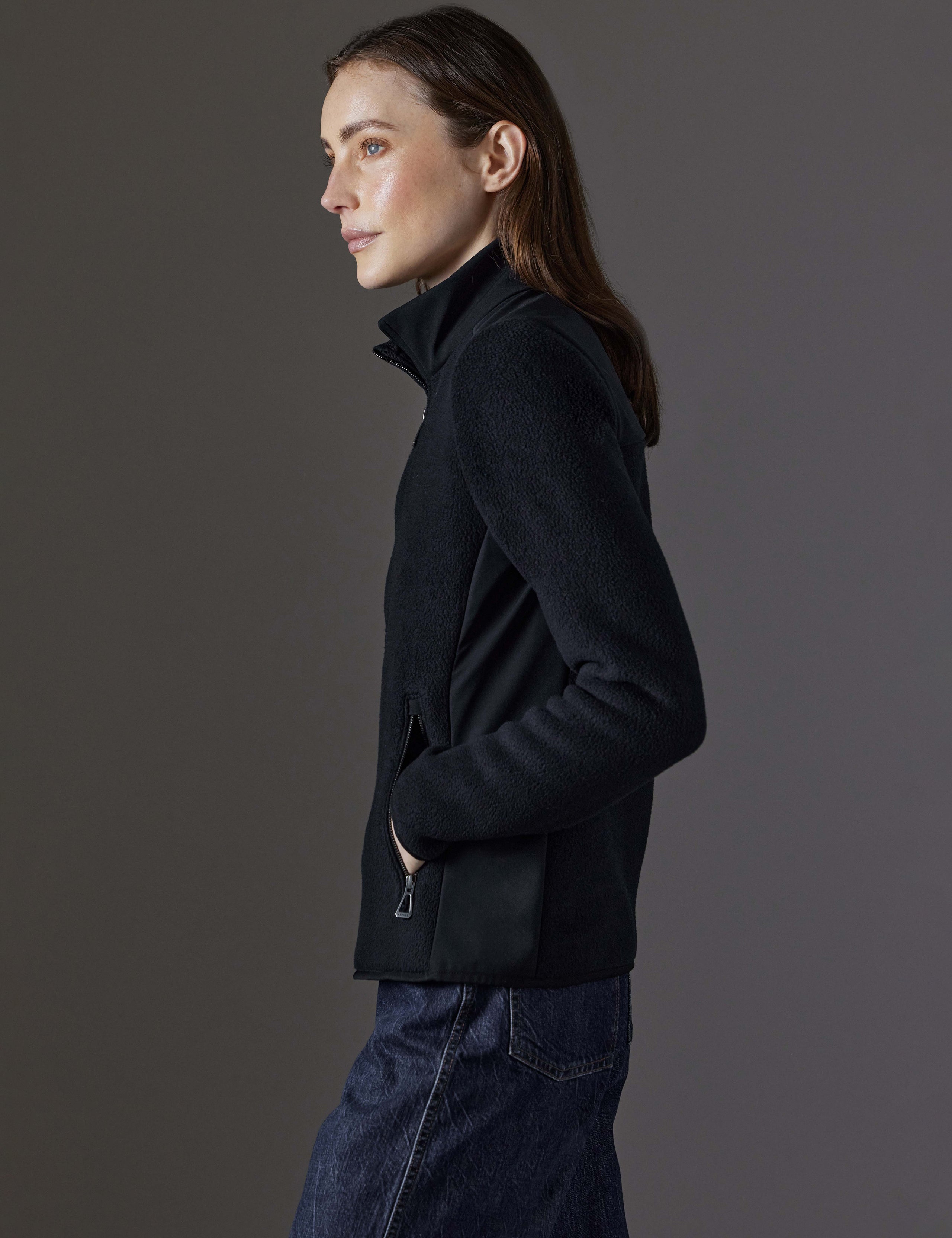 Side profile view of woman wearing Walsh Full-Zip 2.0 in Onyx Black from AETHER Apparel.