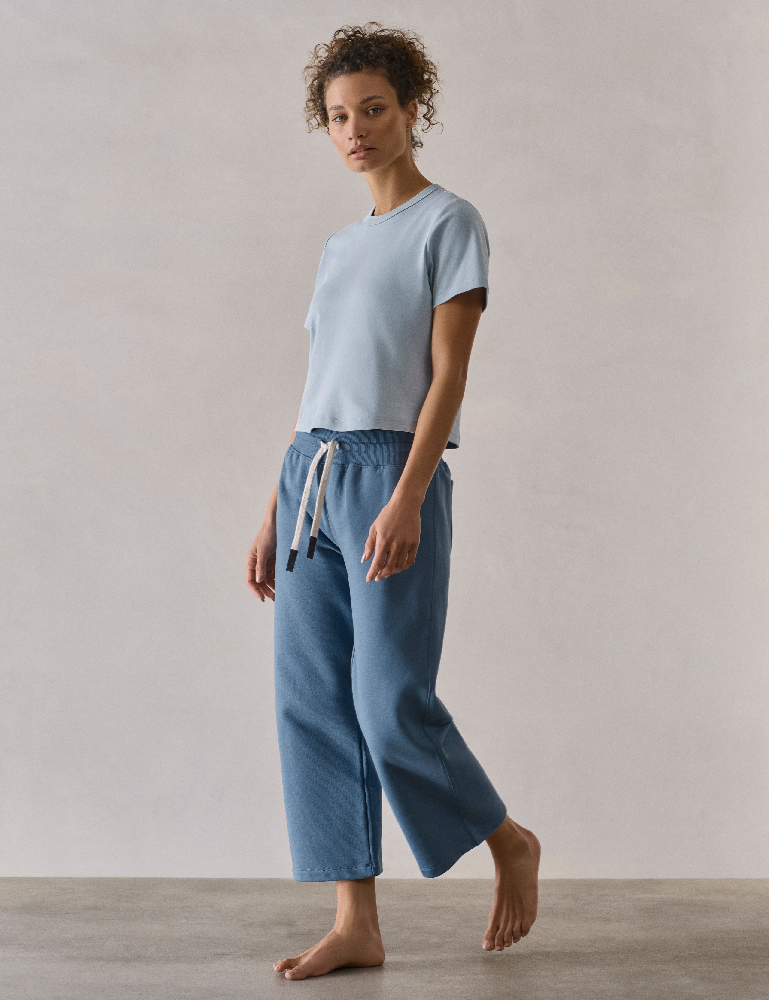 Front 3/4 full-body view of woman wearing W Osa Cropped Sweatpant in Coastal Blue from AETHER Apparel.