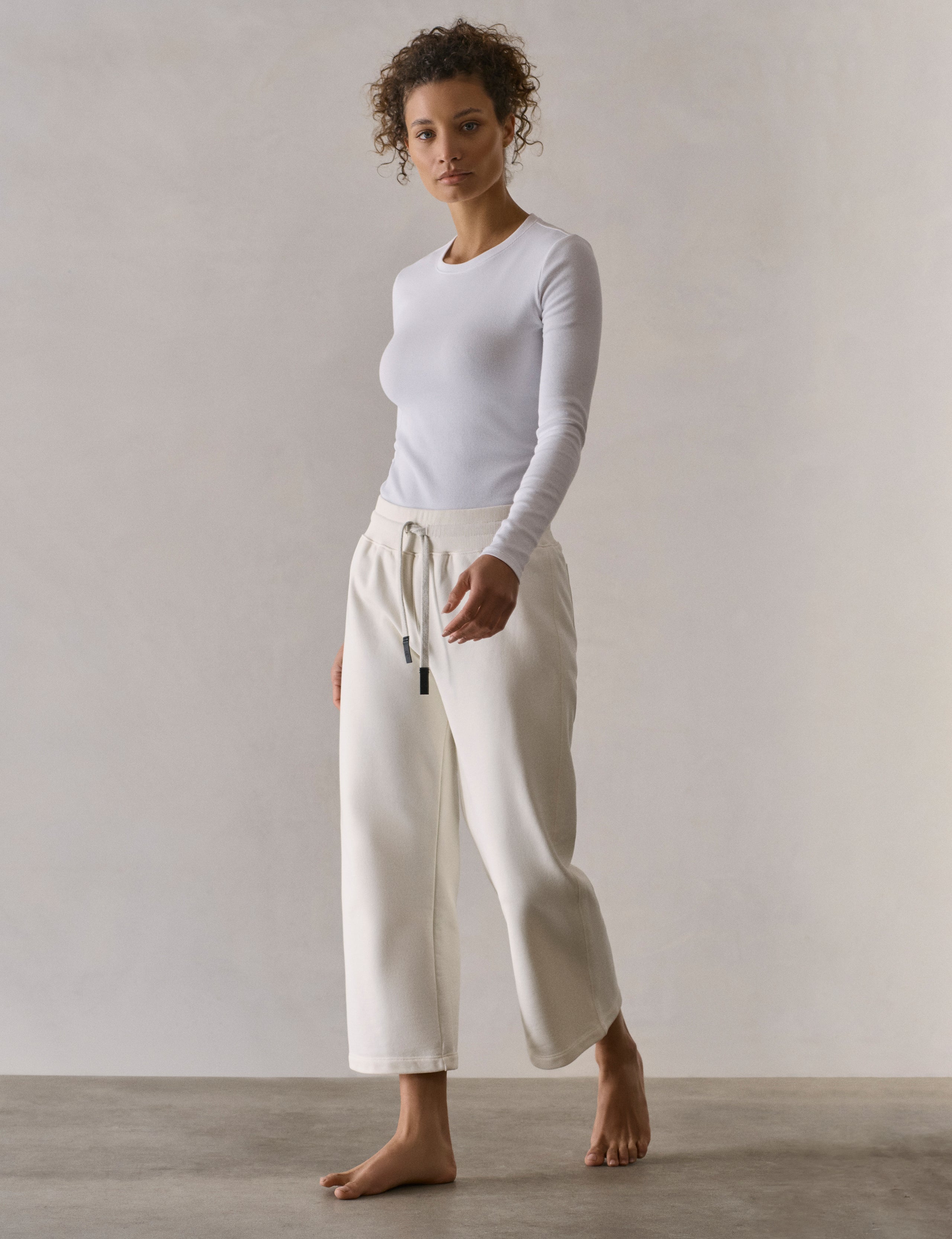 Front 3/4 full-body view of woman wearing W Osa Cropped Sweatpant in Winter White from AETHER Apparel.